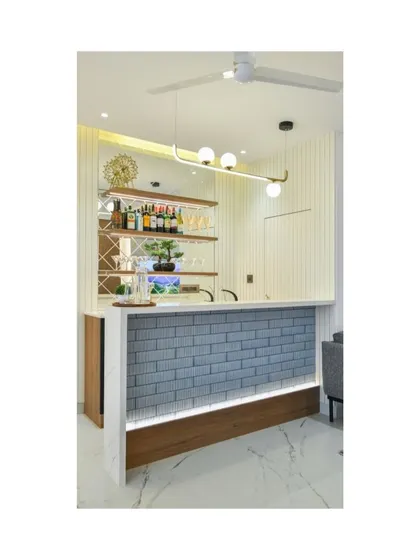 An indoor bar unit designed for clients who love to entertain in style. The design features a grey brick-textured front with under-lighting, a white marble top, and elegant shelving for glassware, creating a chic and functional entertainment hub.