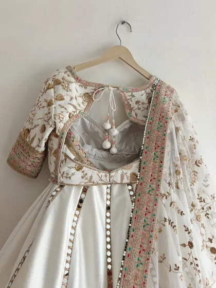 A close-up of the back of the blouse for our new white floral lehenga, showing the stylish keyhole design and delicate tassels.