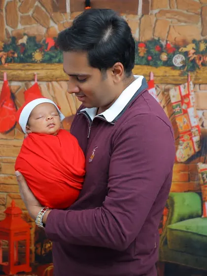 A proud father holds his sleeping newborn during their first Christmas photoshoot. These are the quiet, precious moments that become treasured family memories.