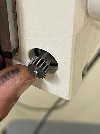 A finger points to the small but crucial gear that was repaired. This image highlights the precision and attention to detail required in advanced repair work.