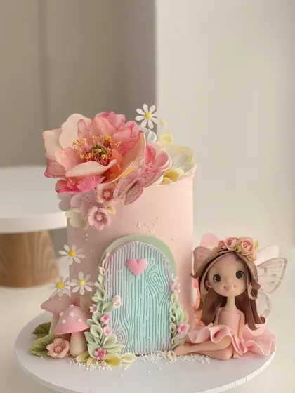 A pretty pink dreamy fairy cake, complete with a fairy door, mushrooms, and a beautifully sculpted fairy figurine.