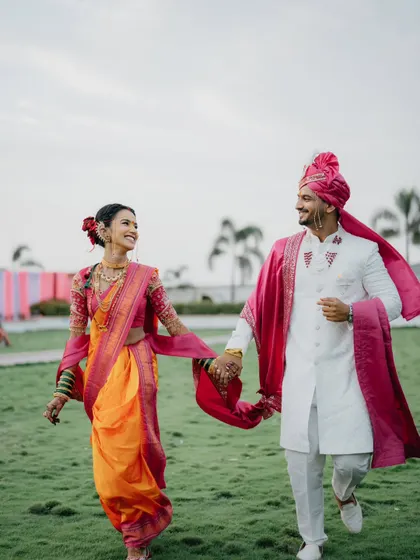 A joyful, candid shot of the couple walking hand-in-hand. The movement in her saree and his shawl adds a dynamic feel to the photo.