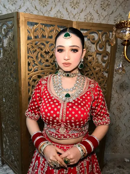 A classic pose showing the beautiful contrast between the red lehenga and the green emeralds.