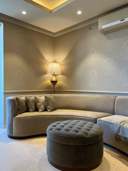 A closer look at the curved sofa and ottoman. The subtle pattern on the wall, created with stencil art, adds a touch of classic detail to the modern furniture forms.