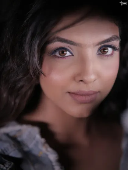 This is a pure beauty portrait, where the eyes tell the story. The tight crop and soft lighting put all the emphasis on the stunning eye makeup and the subject's direct, captivating gaze.