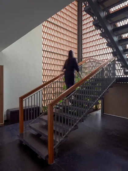 The main staircase is set against a full-height jali wall, transforming the act of circulation into an experience of changing light and shadow.