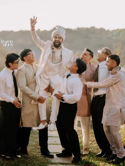 The groom being joyfully lifted by his groomsmen. This is a classic candid moment of friendship and celebration.
