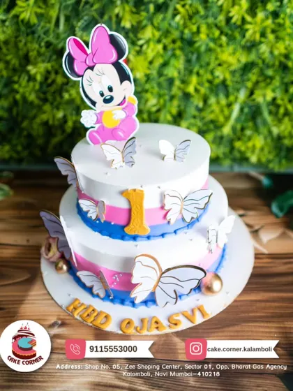 A two-tier Minnie Mouse cake with beautiful butterfly decorations. The pink, blue, and white colours create a soft and magical look for a first birthday.