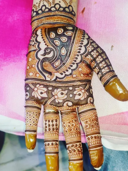 A close-up of a single hand, showing a detailed peacock motif and intricate finger designs.