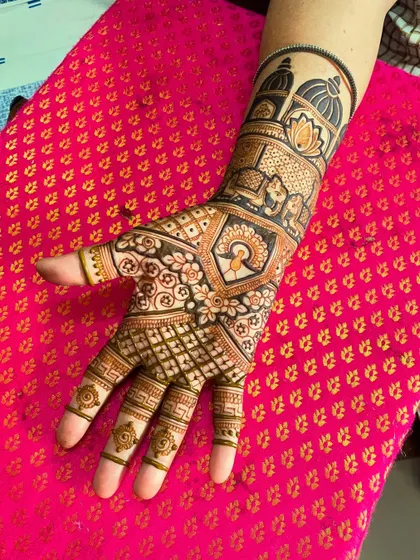 A close-up of a beautiful bridal mehendi. The design features a peacock, a lotus, and architectural domes, all intricately detailed.
