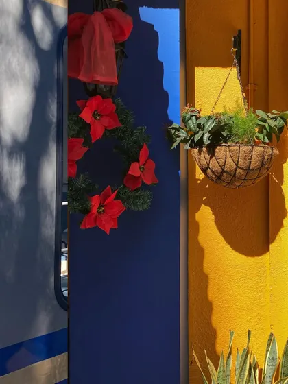 The strong contrast of a bright yellow wall and the deep blue shadow of a train decorated for Christmas.