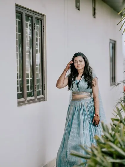 A beautiful outdoor portrait of a bride in a light blue lehenga. The natural light and lush green background create a fresh and serene image, capturing her effortless beauty.