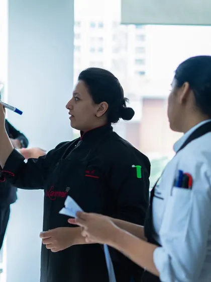 A mentor guiding her students. We believe in the power of mentorship to help our students find their best selves in the kitchen.