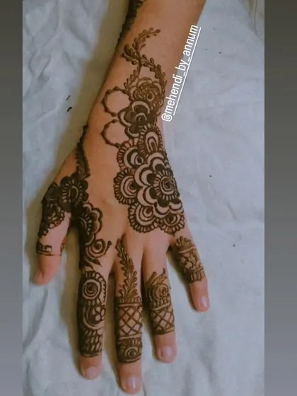 A clean and simple Arabic-style design. The pattern focuses on a central floral element with delicate vines extending towards the fingers, leaving lots of open skin.