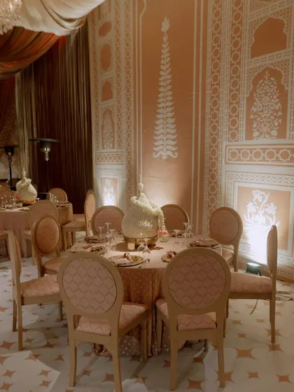 A dining table set against a wall with custom-painted traditional Indian block-print-style patterns. The design creates a cohesive and culturally rich environment.