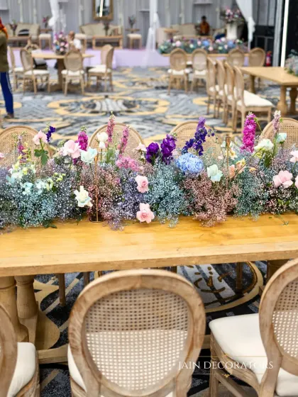 A long table adorned with a runner of colorful baby's breath. This simple yet stunning centerpiece adds a meadow-like, whimsical feel to the guest dining experience.