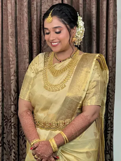 Bride Namita in a beautiful golden tissue silk saree. The soft glow of the saree is complemented by her traditional gold jewellery and jasmine flowers in her hair.