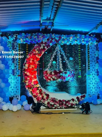 This fairy-themed naming ceremony features a stunning stage with a floral moon-gate, a hanging cradle, and blue balloon columns. The fairy cutouts and intricate backdrop panels add to the magical feel.