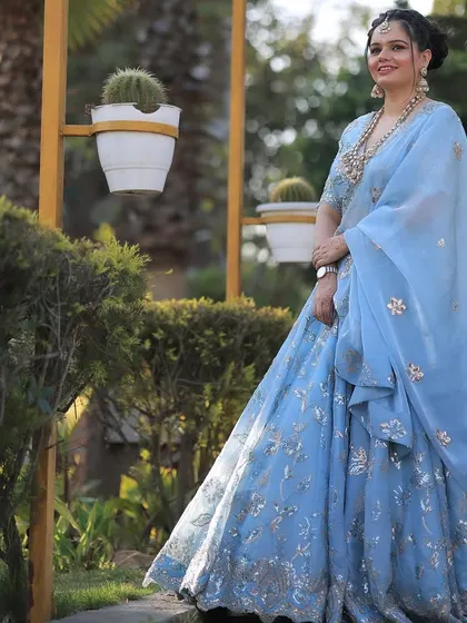 A profile shot against the green bushes, her blue lehenga standing out beautifully.