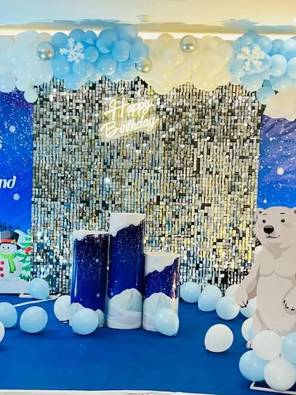 A "Winter ONEDERLAND" first birthday party with a Frozen touch. The setup includes a silver shimmer wall, snowflake details, and a polar bear cutout.