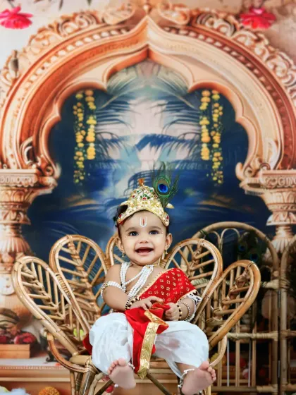Seated like a little prince on a wicker throne, this baby Krishna's joyful smile lights up the entire frame.