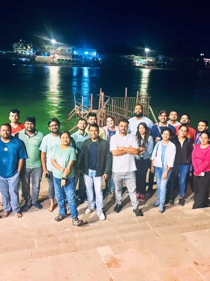 The group posing by the Ganga in Rishikesh at night. Our trips often include stops at iconic locations to complete the experience.