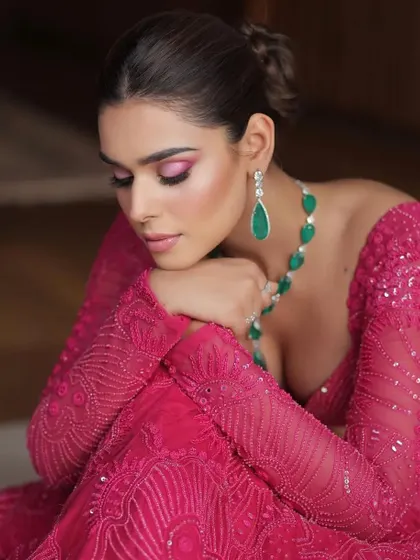 A close-up on the details, showing the intricate embroidery and the stunning emerald drop necklace.