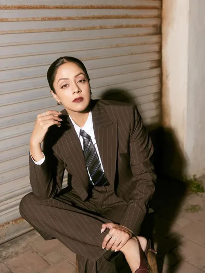 A seated pose that exudes relaxed confidence, showcasing the wide-leg trousers and sharp tailoring.