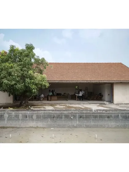 The exterior of the Alibaug house, showing the traditional tiled roof and the large opening of the main living space, which is still under construction.