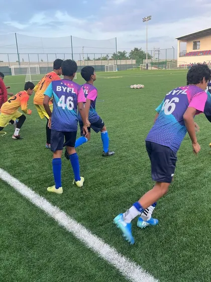 The U15 squad jogging and warming up together at the start of a training session.