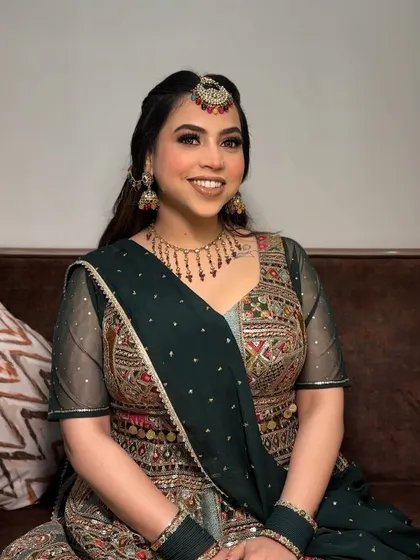 A full view of her festive outfit. The makeup is designed to complement the intricate embroidery and colors of her dress.