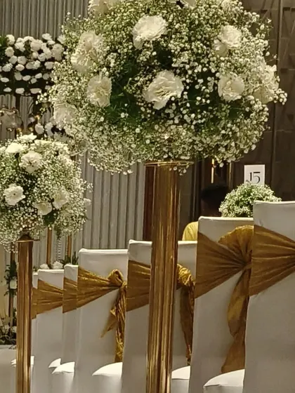 A detailed look at the aisle decor for an elegant wedding. Tall stands with large bouquets of baby's breath and white carnations line the walkway, creating a beautiful floral path.