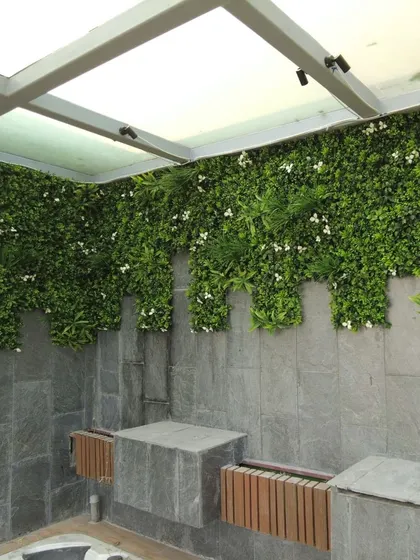 The "after" shot of the terrace jacuzzi area. The space is now transformed with sleek slate stone finishes, a lush artificial green wall, and modern WPC elements, creating a high-end, spa-like atmosphere.