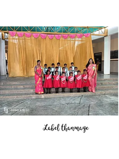 A group of young boys and girls in matching red dresses and formal wear, posing together after their school performance.