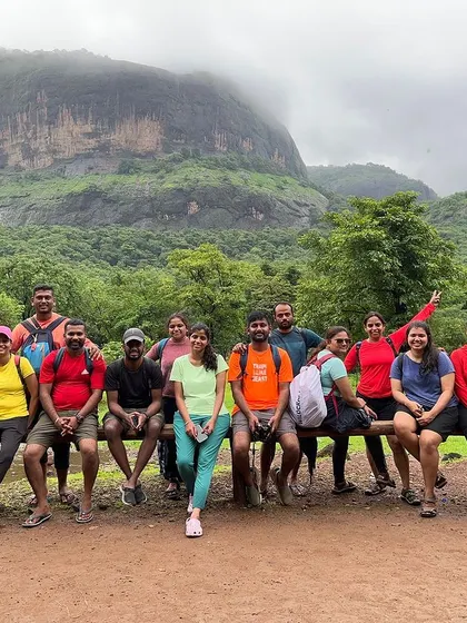 The group takes a break during a trek, with a massive rock monolith in the background. The landscapes in Maharashtra are truly dramatic.