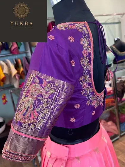 This purple blouse sleeve features a beautiful embroidered motif of a woman, inspired by traditional Indian art. It's a unique and personal touch for a custom-made garment.