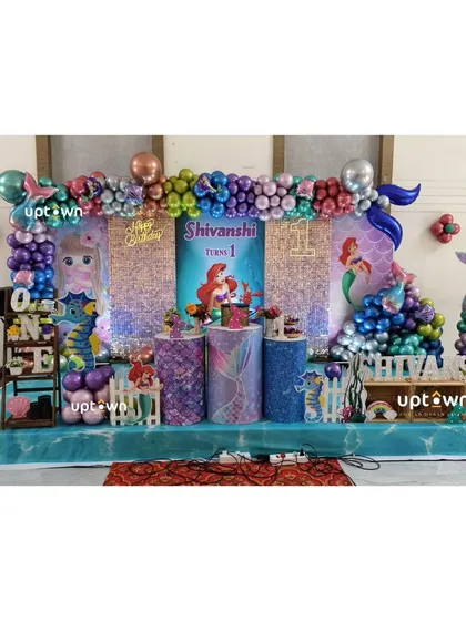 The full stage setup for the mermaid party, with a sequin and character backdrop.