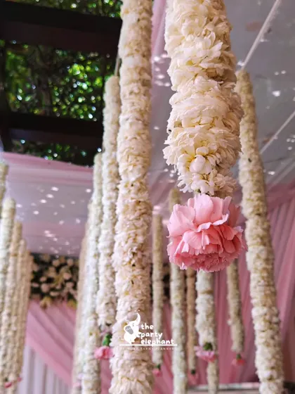 A close-up of the beautiful hanging garlands, showing the texture of the white flowers and the pop of color from the single pink carnation.