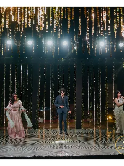 A solo performance on the Sangeet stage, set against a backdrop of hanging crystal strings.