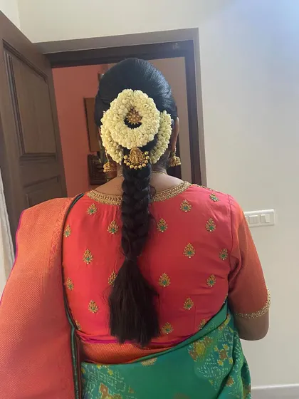 A classic South Indian braid with a neat puff, adorned with a jasmine gajra and a traditional jhumka-style hair accessory.