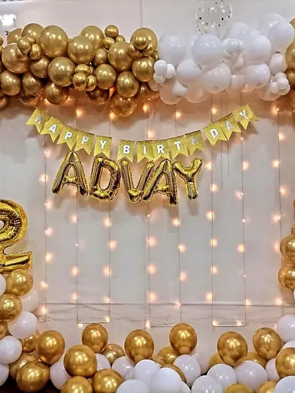 A beautiful gold and white balloon frame decoration for a 12th birthday at home, complete with a fairy light curtain.