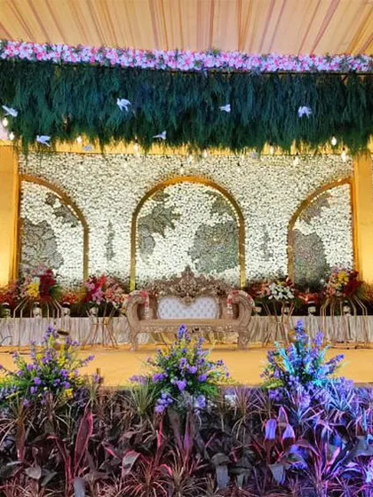 A grand stage with a backdrop of white floral panels carved into world map silhouettes. The design is unique and personalized, perfect for a couple who loves to travel.