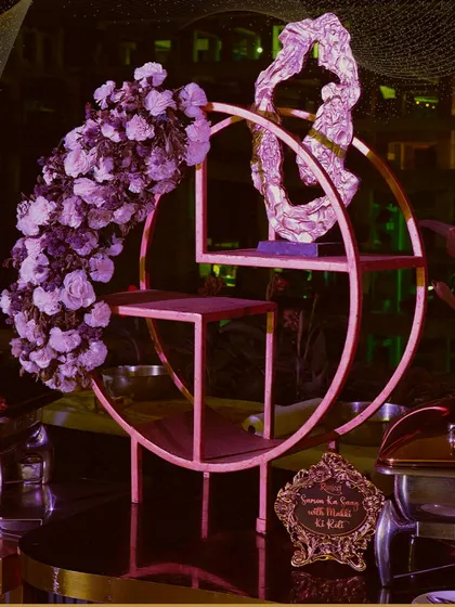Artistry in every detail. This unique circular display stand, adorned with a cascade of purple flowers, serves as a stunning focal point for our dessert or appetizer presentations.