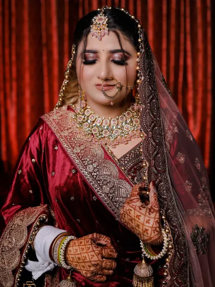A classic portrait of a bride in a deep red velvet lehenga. The soft lighting and her serene expression create a timeless and elegant look.