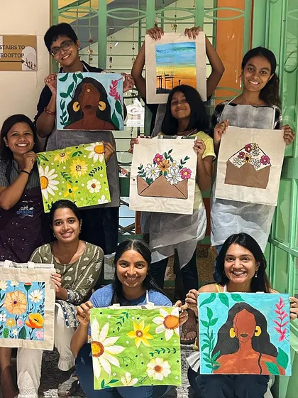 A group of participants showing off the amazing tote bags they painted. The designs are so creative and personal.