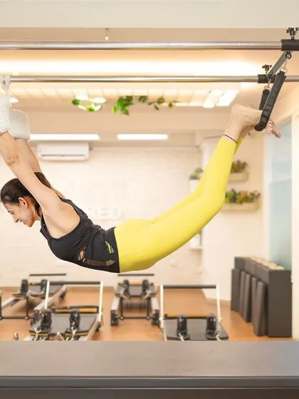 A stunning shot of our founder, Taru, in a hanging pose on the Cadillac, embodying the grace and power of Pilates.