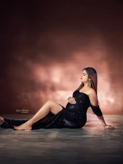 A relaxed yet glamorous pose on the studio floor. The high slit in the gown adds a touch of modern style, while the soft lighting creates a serene mood.
