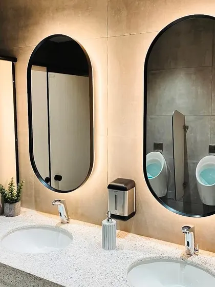 The modern washroom design for the DLF hospitality office. We used terrazzo countertops, backlit oval mirrors, and clean finishes to maintain a sophisticated and cohesive aesthetic throughout the entire workspace.