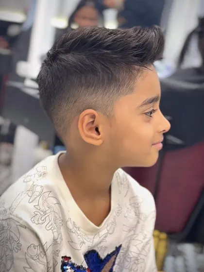 This little man is rocking a stylish haircut with a high fade and textured top.