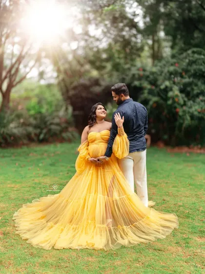 A romantic outdoor couple's maternity photo. The golden hour light and the lush green background create a perfect setting to capture the love between expecting parents.